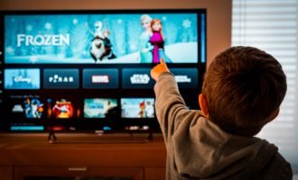 Barcelona, Spain. May 2019: Back view image of cute little boy watching the new Disney plus streaming service and pointing at the TV screen.Illustrative editorial